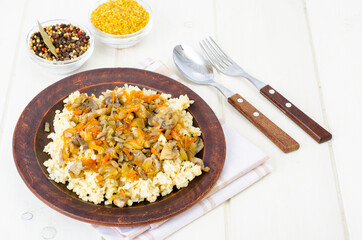 Tasty boiled porridge with vegetables and mushrooms.