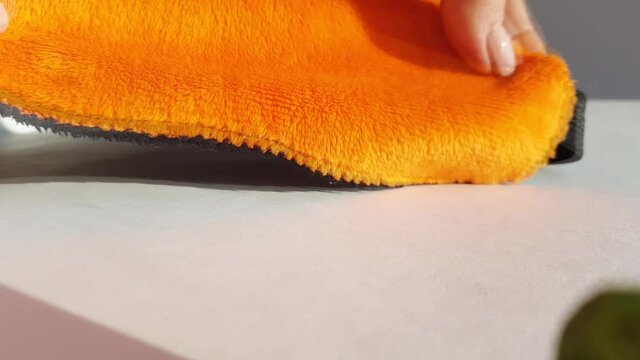 A woman's hand strokes a soft orange sleep mask lying on a white background with bright sunlight in the morning. Healthy sleep concept, 4k video