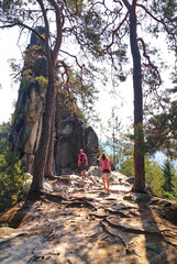 
two people go to a rock in the woods among the trees