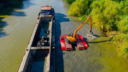 Aerial view of river, canal is being dredged by excavator