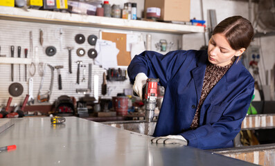 Woman apprentice drills hole with screwdriver. High quality photo