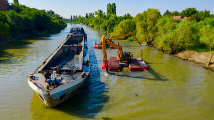 Aerial view of river, canal is being dredged by excavators