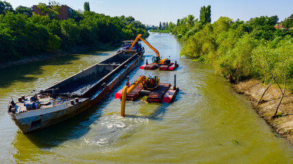 Aerial view of river, canal is being dredged by excavators