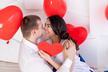 valentine's day, a guy with a beautiful girl look at each other with a loving look, which holds a big red heart