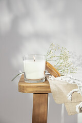 White burning candle and delicate flowers on wooden bench