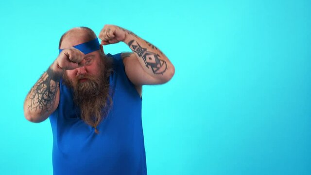 Chubby man training and making sport. Big hipster guy with tattoos at the gym