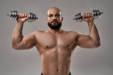 Fototapeta na wymiar Young muscular caucasian athlete lifting dumbbells