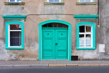 Old neglected abandoned white townhouse with green doors and windows somewhere in the south of Poland