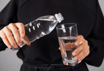 Woman pouring water from bottle into glass.