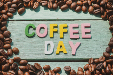 Roasted coffee beans and Coffee Day alphabets on wooden background.
