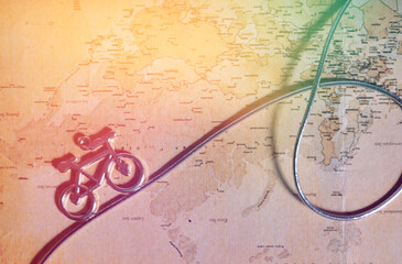 An old map with a line and a toy bicycle on it. The concept of travel