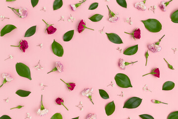 Pattern made of flowers and green leaves on a pink background with copy space. Greeting card concept.
