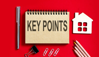 KEY POINTS text writtenon red background on a notebook with pencils and office tools and model...