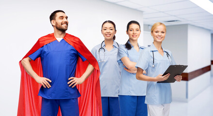 healthcare, profession and medicine concept - happy smiling male doctor in blue uniform and red superhero cape and female nurses over hospital corridor background © Syda Productions