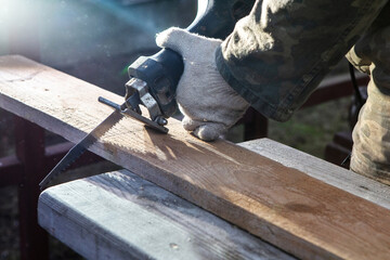Hands of a joiner with a electric saw. Wooden board. The work of a professional. Woodworking industry. Woodwork.