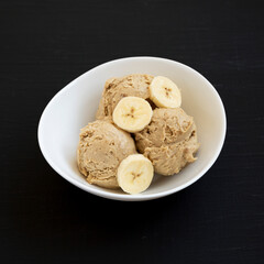 Homemade Peanut Butter Banana Ice Cream in a Bowl on a black surface, low angle view.