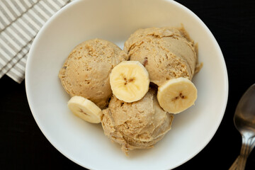 Homemade Peanut Butter Banana Ice Cream in a Bowl on a black surface, top view. Flat lay, overhead,...