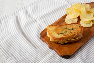 Homemade French Onion Melt Cheese Sandwich with Chips on a rustic wooden board on cloth, side view. Copy space.