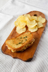 Homemade French Onion Melt Cheese Sandwich with Chips on a rustic wooden board on cloth, low angle view.