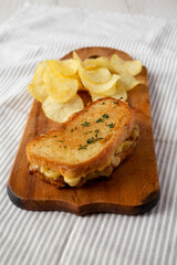 Homemade French Onion Melt Cheese Sandwich with Chips on a rustic wooden board on cloth, side view.