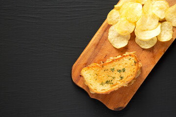 Homemade French Onion Melt Cheese Sandwich with Chips on a rustic wooden board on a black background, top view. Flat lay, overhead, from above. Copy space.