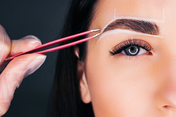 We make eyebrows with pink tweezers, close-up background for the eyebrow.