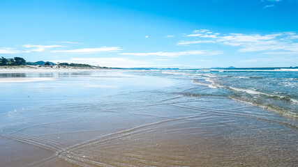 Long white sand beach with blue sky in New Zealand. Pakiri Beach north island. 