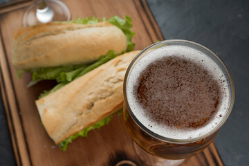Sandwiches and beer on a wooden table, close up