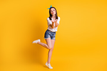 Fototapeta na wymiar Full length body size view of lovely flirty brown-haired girl jumping sending air kiss isolated over bright yellow color background