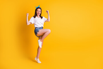 Fototapeta na wymiar Full length body size view of lovely cheerful brown-haired girl jumping rejoicing isolated over bright yellow color background