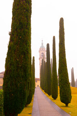 Walkway with Cypress Tree and Parish of Sant'Abbondio in Montagnola in Ticino, Switzerland.