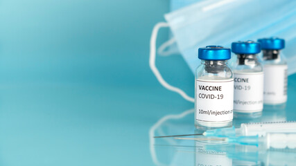 Coronavirus vaccine vials. Corvid 19 vaccination with vaccine glass bottles, syringes and protective face masks. Blue background.