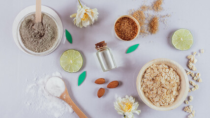 natural skin care products: backing soda, clay powder, brown sugar, almond oil, oats. Colorful background of natural cosmetics and flowers. natural ingredients for body scrubs on purple background