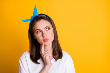 Photo of minded young woman look empty space finger on chin isolated on bright yellow color...