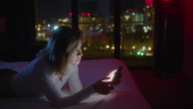 Woman lay down on bed and use of mobile phone at night