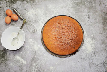 Homemade sponge cake, part of the ingredients and utensils On a stone base and zenith view.