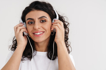 Happy brunette girl smiling while listening music with headphones