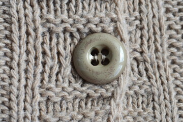 Four hole button on knitted beige fabric