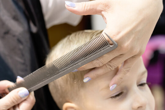 Close-up of hairdresser styling boy's hair at the salon.