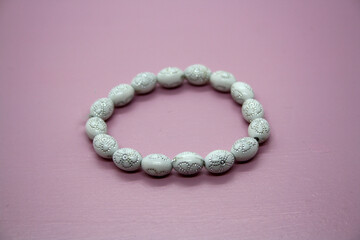A bracelet made of beads on a pink background.