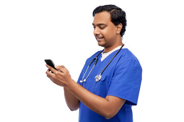 medicine, healthcare and technology concept - happy smiling indian doctor or male nurse in blue uniform with stethoscope using smartphone over white background