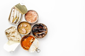 Assortment of cans of canned food with different types of fish Salmon, tuna, mackerel and sprats and seafood against white background with copy space for your text
