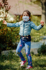 Fototapeta premium Young girl playing outdoors during the pandemic year of 2021