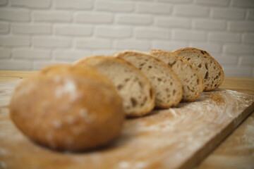 Bread sliced and freshly baked on a wooden table. Flour, bakery. The cooking process is captured in 4k resolution. White brick background. Selective Focus