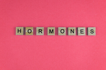 Word hormones. The phrase is laid out in wooden letters. Top view. Motivation. Blue background. Copy space