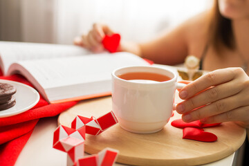 girl reads a book about love over a cup of tea, valentine's day morning, hearts