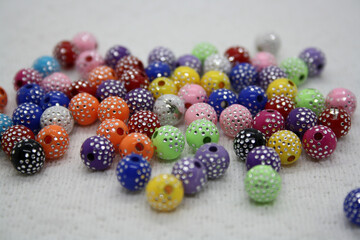 Colorful beads on a white textile background.