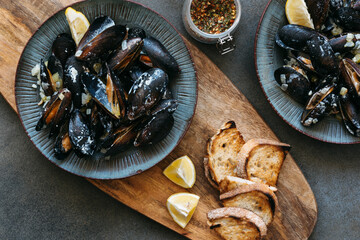 Cooked shell mussels in cheese sauce with lemon in ceramic plates.
