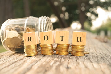 Close up of stacking coins and wooden blocks with text ROTH. Business and finance concept