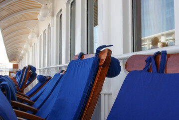 Elegant wooden teak deck chairs and sun loungers with blue covers on luxury cruiseship or cruise...
